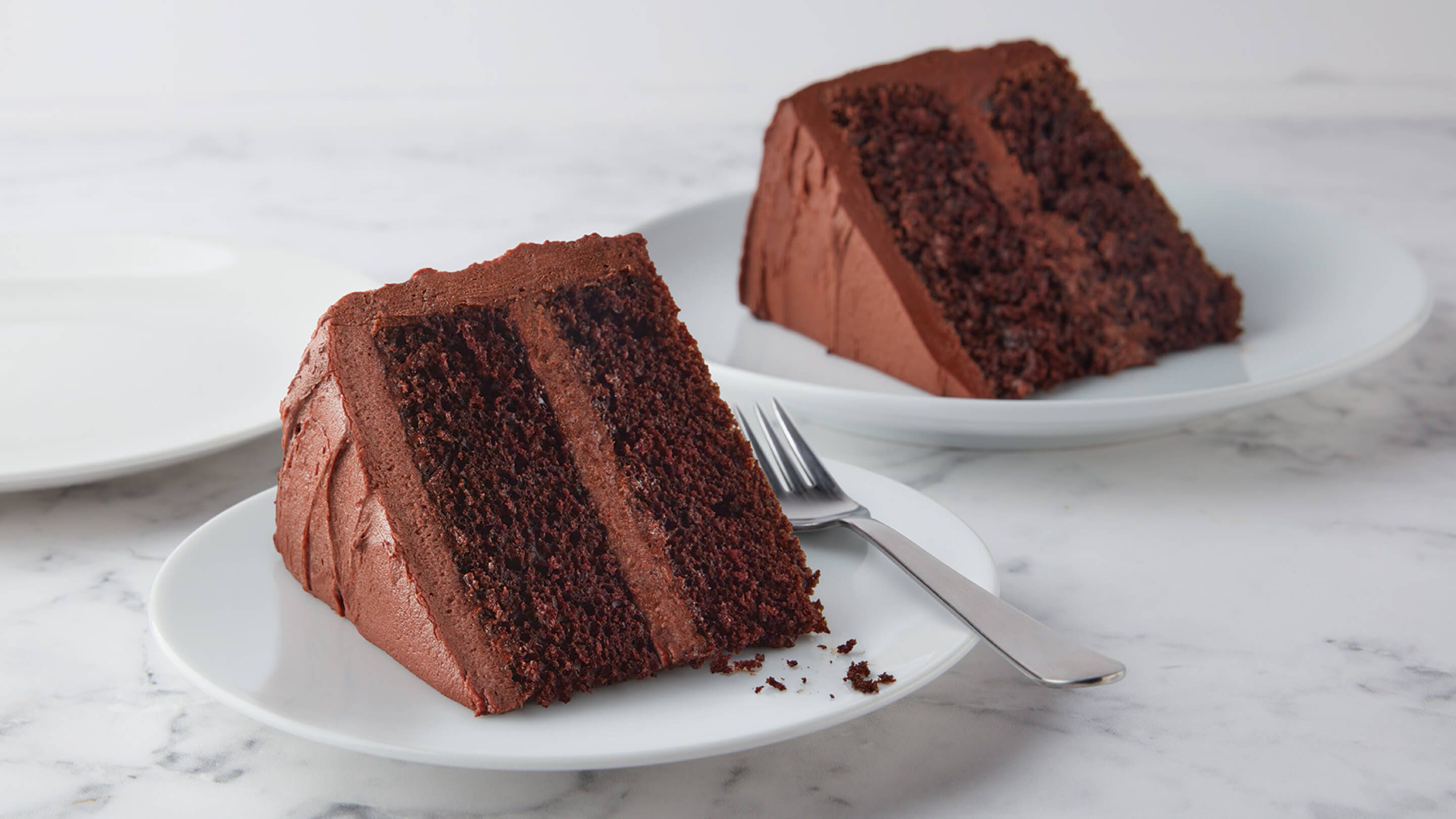 two plated slices of iced chocolate cake