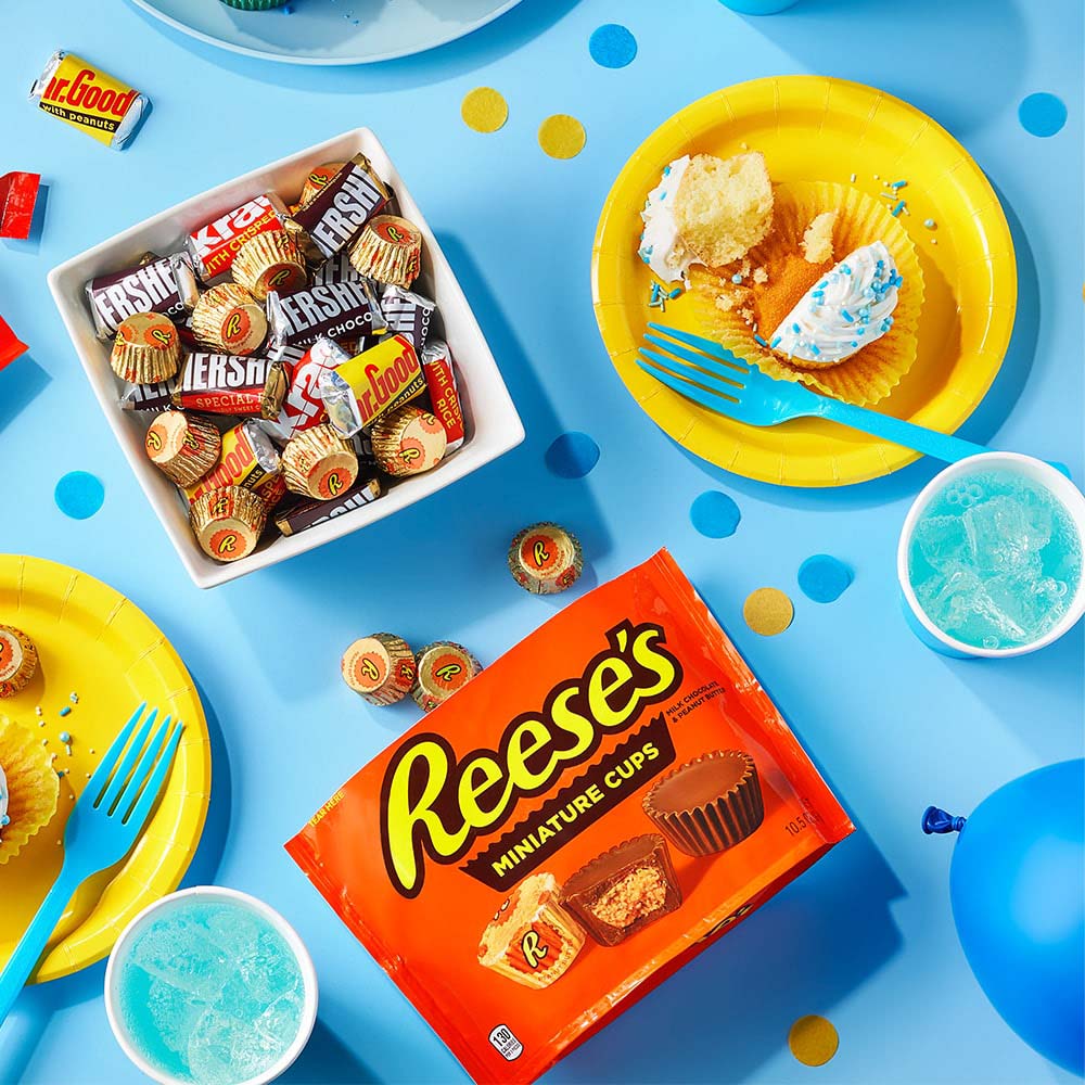 table filled with party decorations, candy, and freshly made cupcakes